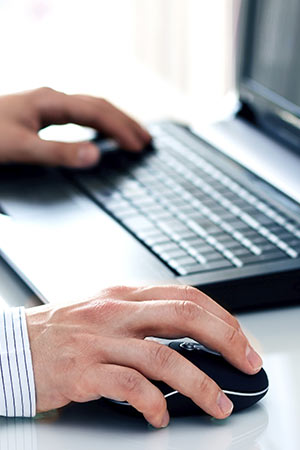 a person using a laptop computer sitting on top of a desk